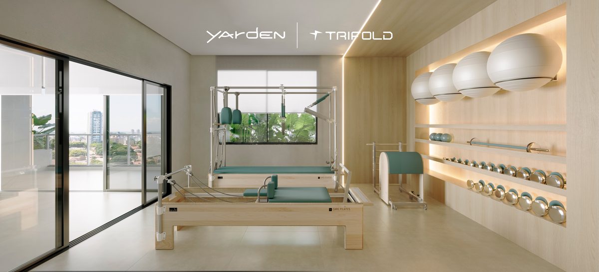 Sala de pilates do rooftop do Yarden, com aparelhos e parede de madeira